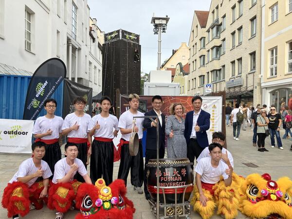 Bild vergr&ouml;&szlig;ern: L&ouml;wentanzgruppe mit Delegationsmitgliedern aus Foshan und Amtsleiterin Christina Diederichs in der Fu&szlig;g&auml;ngerzone