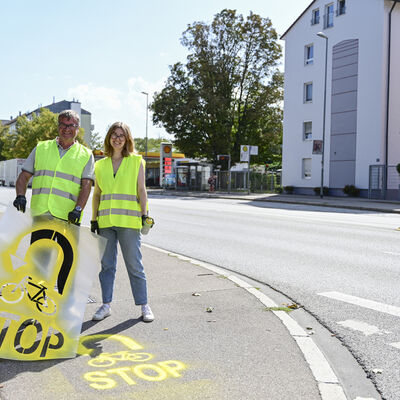Fahrradbeauftragte Theresa Schneider und Ulrich Sch&auml;pe, Leiter des Amts f&uuml;r Verkehrsmanagement und Geoinformation, bringen Hinweise auf dem Fahrradweg auf. 